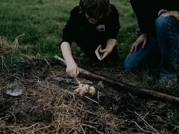 Jugendlicher beim Anzünden eines Lagerfeuers